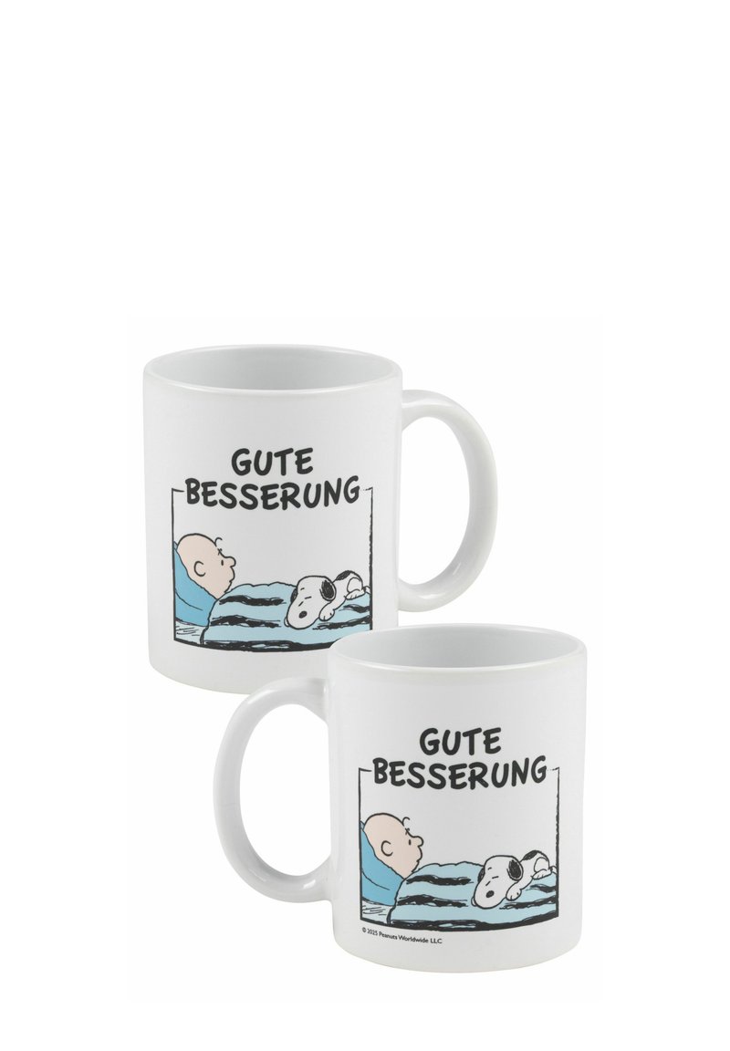 Mug in ceramica bianca con un design che raffigura un personaggio a letto e un cane, insieme al testo "GUTE BESSEERUNG" in grassetto nero.