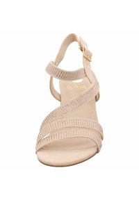 Beige sandal med korsade remmar som har glittrande rhinestones. Klacken är öppen framtill, med ett spänne runt ankeln. Slät textur.