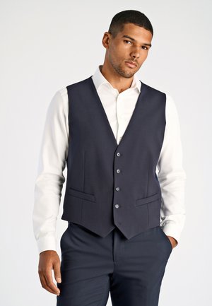 Gilet senza maniche navy con una vestibilità su misura, caratterizzato da un collo a V, chiusura con cinque bottoni e tasche laterali, indossato sopra una camicia bianca.