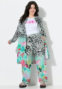 Lichtgewicht blouse met lange mouwen in een contrasterend zwart-wit luipaardmotief, gecombineerd met teal pants met tropische bloemen- en tijger patronen.