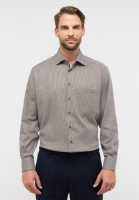 Camicia a maniche lunghe a quadri in beige e marrone con colletto, taschino frontale e bottoni scuri. Tessuto liscio con vestibilità su misura.