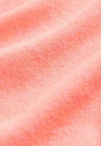 Svijetloružičasta tkanina s mekom, glatkom teksturom, s diskretnim uzorkom pletenja i blagim varijacijama boje na cijeloj površini.