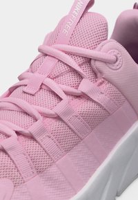 Κοντινή λήψη ροζ αθλητικού παπουτσιού Nike Free με αεριζόμενο άνω μέρος από δίχτυ, κορδόνια με θηλιές και παχύ λευκό πάτο.