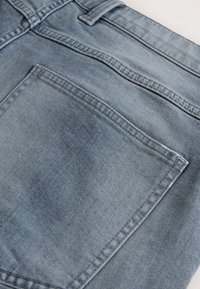 Jeans aus Denim mit einem hellblauen Waschung, ausgestattet mit einer Gesäßtasche, Standardnähten und einem flachen Bunddesign.