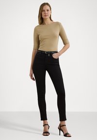Beige tettskjorte med trekvart ermer, parret med svarte høytaljede jeans og svarte heler med stropper. Enkel og moderne design.
