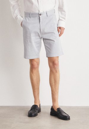Hellgraue Baumwollshorts mit geradem Schnitt, vorderen Taschen und Knopfverschluss, kombiniert mit schwarzen Lederloafern.