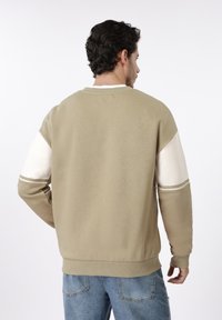 Φούτερ από βαμβακερό μείγμα σε απαλό μπεζ χρώμα με αντίθετα λευκά και μπεζ μανίκια. Διαθέτει ριμπ κολάρο και μανσέτες, άνετη εφαρμογή.