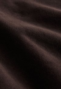 Close-up of dark brown ribbed fabric texture with soft folds and subtle shadows.