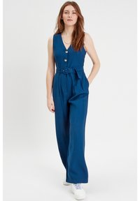 Tuta senza maniche blu con scollatura a V, chiusura con bottoni e vita regolabile con cintura. Presenta pantaloni a gamba larga e una texture liscia.