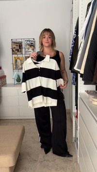 Pruhované černo-bílé polo tričko s krátkým rukávem a sklopeným límečkem, které má uvolněný střih a mírně oversized fit.