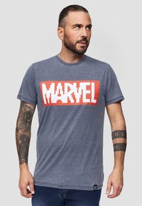 Šedé bavlněné tričko s odvážným pixelovaným grafickým prvkem „MARVEL“ v červené a bílé barvě na hrudi; krátké rukávy a kulatý výstřih.