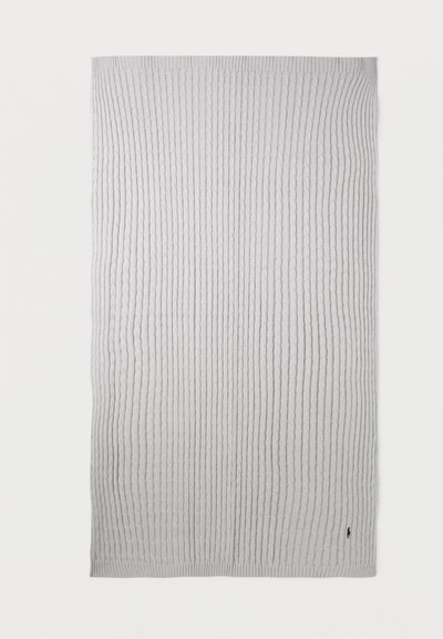 Ανοιχτό γκρι πλεκτή κουβέρτα με κατακόρυφα πλεκτά σχέδια και μικρό σκούρο κεντημένο λογότυπο στην κάτω δεξιά γωνία.