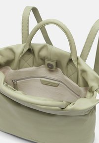 Sac à main en cuir vert clair avec deux poignées, une poche intérieure zippée et une texture lisse. Il dispose d'une doublure douce et d'une fermeture à pression.