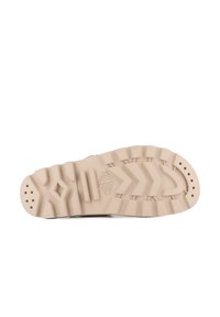 Beige sneakersula med texturerad gummi. Har spår och prickar för grepp och visar varumärket inpräntat i designen.