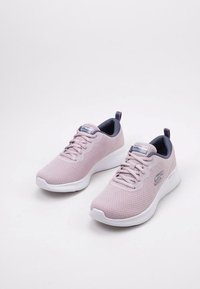 Scarpe sportive rosa chiaro con tomaia in rete testurizzata, suola bianca e accenti blu scuro sul collo e sul logo. Presentano un design con lacci.