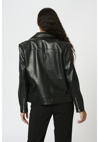 Svart läderjacka med krage, utformad med långa ärmar, sidodragkedjor och en slät textur. Har en figurnära silhuett.