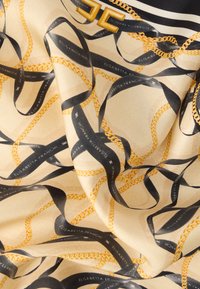 Μεταξωτό φουλάρι με μπεζ φόντο, διακοσμημένο με χρυσές αλυσίδες και μαύρες κορδέλες. Το κείμενο κατά μήκος των κορδελών γράφει "ELISABETTA FRANCHI".