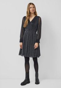 Zwarte lange mouwen jurk met een V-hals, textuurstof, geplisseerde rok en een getailleerde taille. Draagt het met zwarte enkellaarsjes en panty’s.