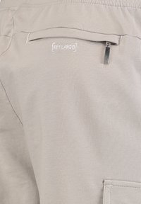 Shorts gris clair avec une texture lisse, dotés d'une poche arrière, d'une fermeture éclair et d'un logo "KEY LARGO" brodé.