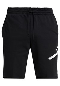 Mustat urheilushortsit, joissa on joustava vyötärönauha, kiristysnyöri ja valkoinen logokuvio vasemmalla puolella. Sileä kangaspinta.