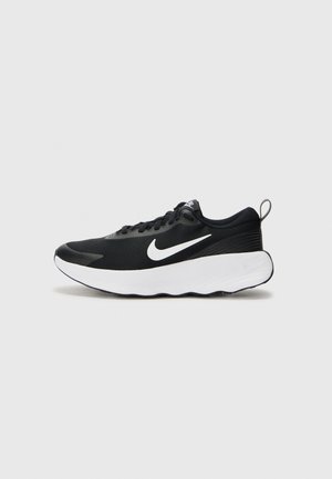 Zwart-witte Nike hardloopschoen met een dikke witte zool, zwart mesh bovenwerk, wit Nike Swoosh-logo en gevoerde hieltabs.