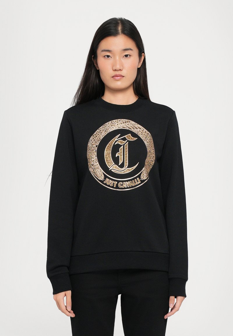 Schwarzer Pullover mit langen Ärmeln, der auf der Vorderseite ein runden Logo-Design in Gold und Schwarz aufweist. Gerippte Bündchen und Saum, glatte Stoffoberfläche.