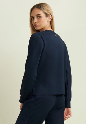 Felpa blu navy con scollo rotondo, polsini a costine e un logo leggermente impresso sul retro. Realizzata in morbido tessuto testurizzato.