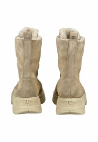 Botas de tobillo de ante beige con un interior suave. Suelas gruesas beige con un diseño texturizado y un pequeño logotipo metálico en la parte trasera superior.