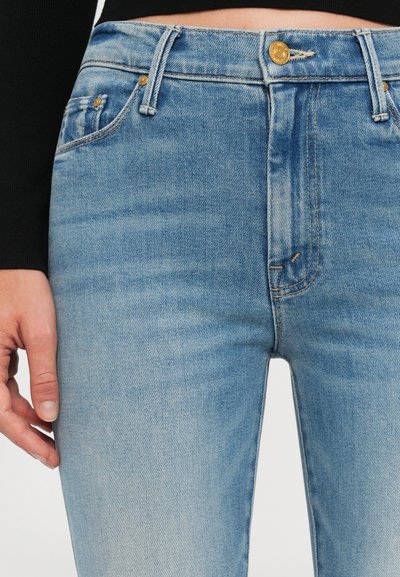 Heledsinine denim teksad, millel on kerge kulumine, traditsioonilise viie taskuga disain, kuldne nööpkinne ja õmblusdetailid.