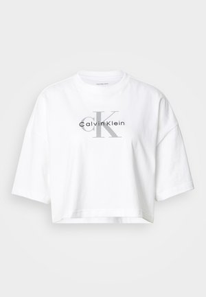 Bela prekratka majica s prevelikimi rokavi, s poudarjenim velikim sivim napisom "CK" in črnim logotipom "Calvin Klein" na sredini sprednje strani.