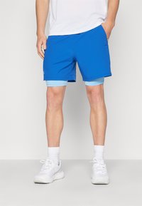 Pantalones cortos deportivos azules con una textura suave, que presentan un forro interior de color azul claro. Llevado con zapatillas blancas y calcetas de longitud media.