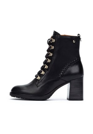 Bottine en cuir noir avec un bout rond, des œillets dorés et un design à lacets. Elle possède un talon bloc et une accent tressée sur le côté.