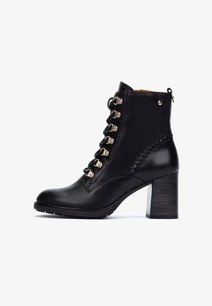 Botín negro de cuero hasta el tobillo con punta redonda, ojetes dorados y diseño de cordones. Presenta un tacón cuadrado y un detalle trenzado en el lateral.