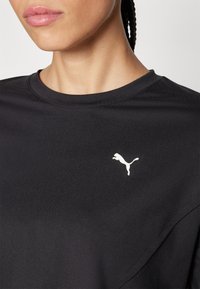 Schwarzes T-Shirt mit Rundhalsausschnitt und kurzen Ärmeln. Verfügt über ein weißes, auf die linke Brust gesticktes Puma-Logo. Glatte Textur.