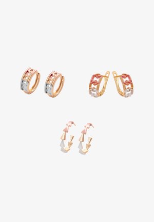 Trzy pary trójkolorowych złotych kolczyków-kołków z ogniwami łańcuszka, ustami oraz wzorami strzałek w kształcie szewronu na białym tle.