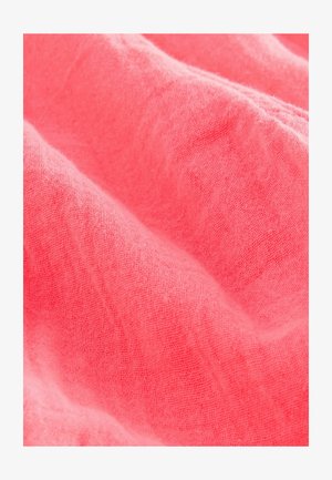Tessuto di lino rosa corallo con una superficie morbida e testurizzata, caratterizzato da pieghe delicate e un aspetto leggero e traspirante.
