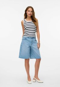 Gestreepte mouwloze top in zwart en wit, gecombineerd met lichtblauwe denim shorts, met een relaxte pasvorm en lengte boven de knie. Witte blokhak schoenen.