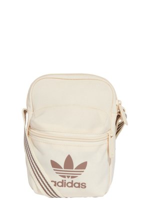 Borsa di colore crema in tessuto con chiusura con zip. Presenta un logo Adidas marrone e una fascia regolabile a righe. Design compatto.