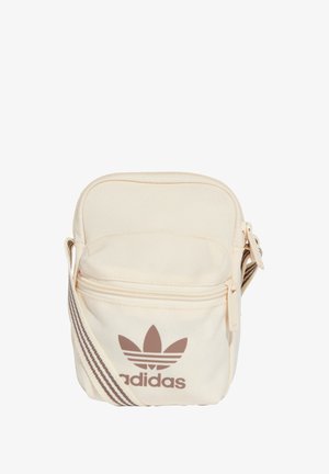 Borsa di colore crema in tessuto con chiusura con zip. Presenta un logo Adidas marrone e una fascia regolabile a righe. Design compatto.