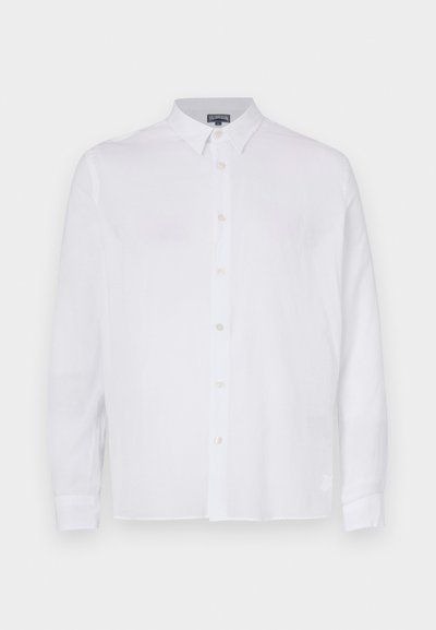 Camisa blanca de manga larga abotonada en tejido de lino con cuello, que presenta un corte recto y botones visibles en el frente.