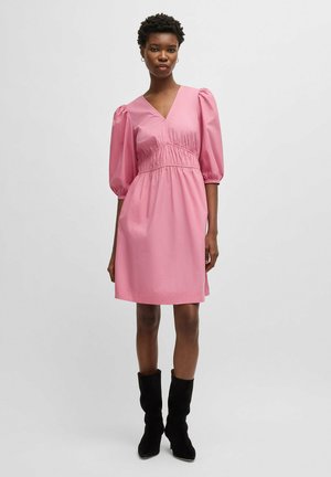 Pink short dress with puff sleeves, V-neck, gathered waistline, and a smooth texture, paired with black knee-high boots.