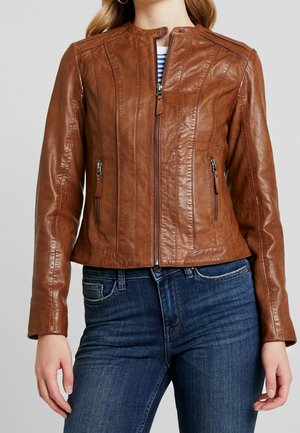 Braune Lederjacke mit hohem Kragen, horizontaler Naht und Reißverschlusstaschen. Getragen mit dunklen Jeans, die eine glatte Textur und eine taillierte Passform haben.