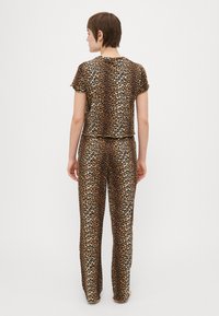 Set de pijama cu imprimeu de leopard, compus dintr-un top cu mâneci scurte și pantaloni lungi, realizat dintr-un material neted, cu o siluetă ajustată și talie elastică.