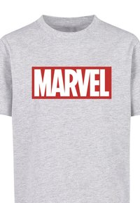 Pilkas medvilninis marškinėliai su ryškiu raudonu stačiakampiu logotipu, kuriame užrašyta "MARVEL" baltomis raidėmis. Marškinėliai turi trumpas rankoves ir apvalų kaklą.