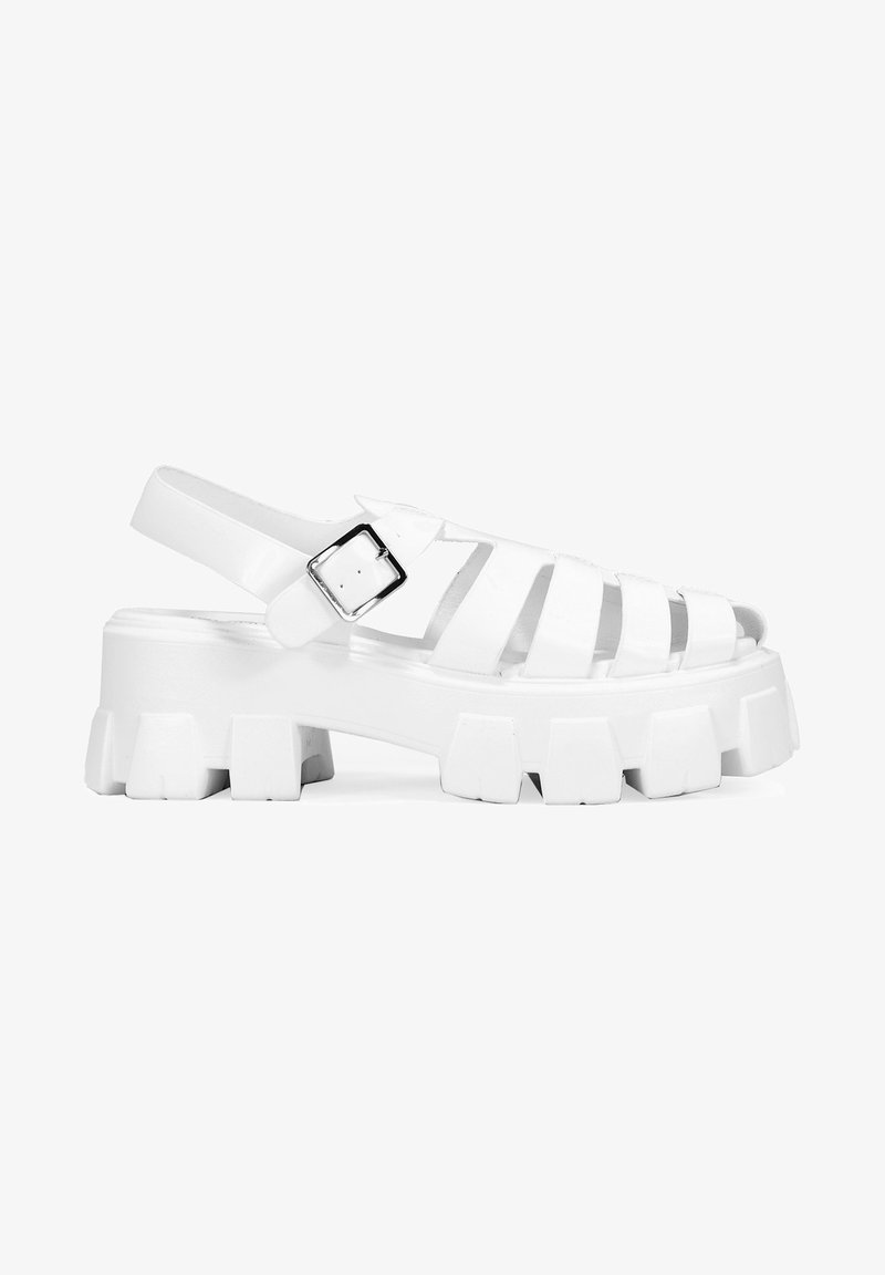 Sandalias de plataforma blancas con múltiples recortes, correa ajustable en el tobillo y suela gruesa con surcos pronunciados y textura suave.