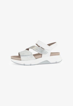 White sandal featuring cross straps in metallic silver and textured white material. The sole is cushioned and features a light gray tread.