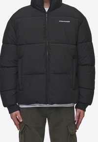 Sort polstret jakke med høj krave, forreste lynlås, elastiske manchetter og et PEGAADOR-logo på brystet. Har en quiltet struktur.