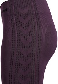 Close-up of purple seamless leggings with vertical chevron patterns and textured stripes along the thigh and hip area.