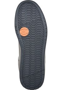 Shoe sole with textured black rubber, featuring a brown circular accent in the center and a zigzag tread pattern for grip.