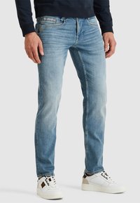 Ljusblå denimjeans med rak passform, med något urtvättade områden, kontrasterande sömmar och en femficksdesign. Bärs tillsammans med vita sneakers.